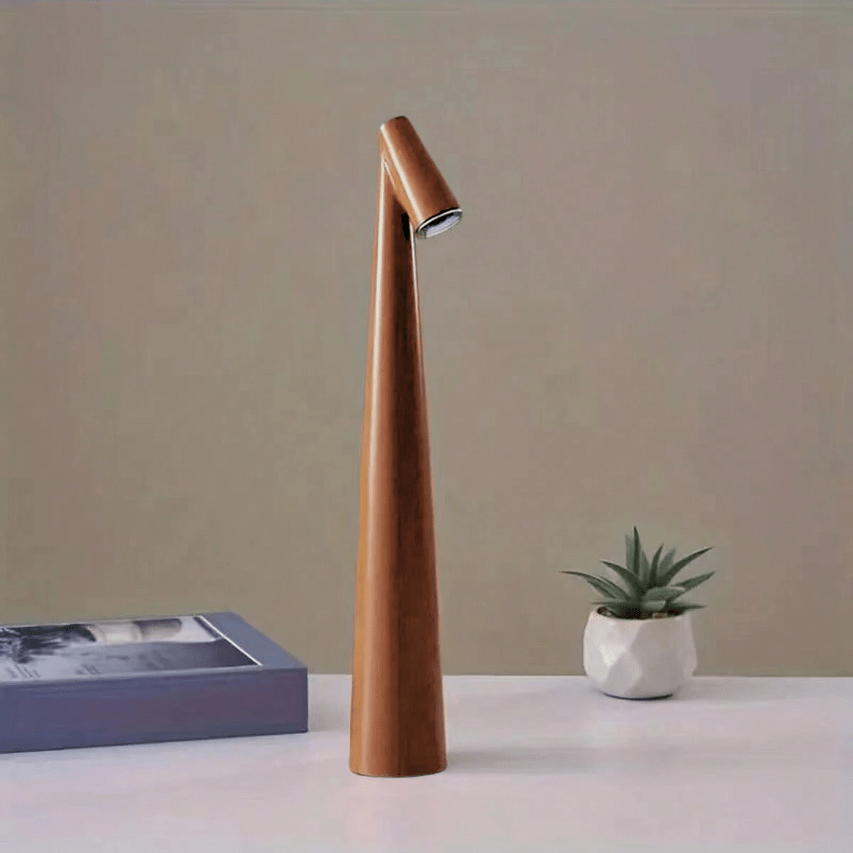NordicSilhouette lampada da tavolo scandinava ricaricabile dalla forma conica: versione marrone su un tavolo bianco accanto a una pianta - Luximode