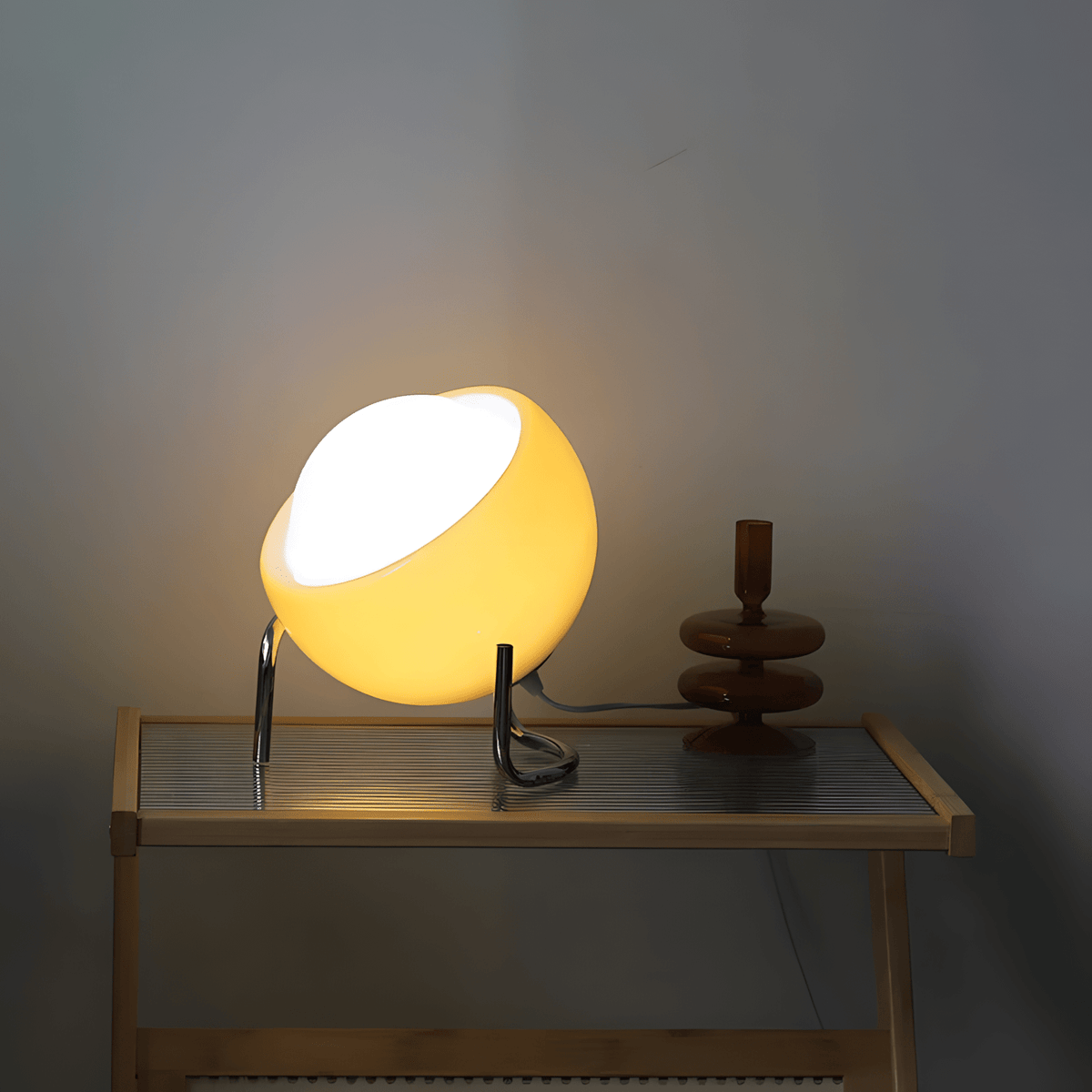 Bauhaus lampada da tavolo in vetro arancione e metallo cromato: lampada accesa su una consolle accanto a un candelabro rosso, vista frontale - Luximode