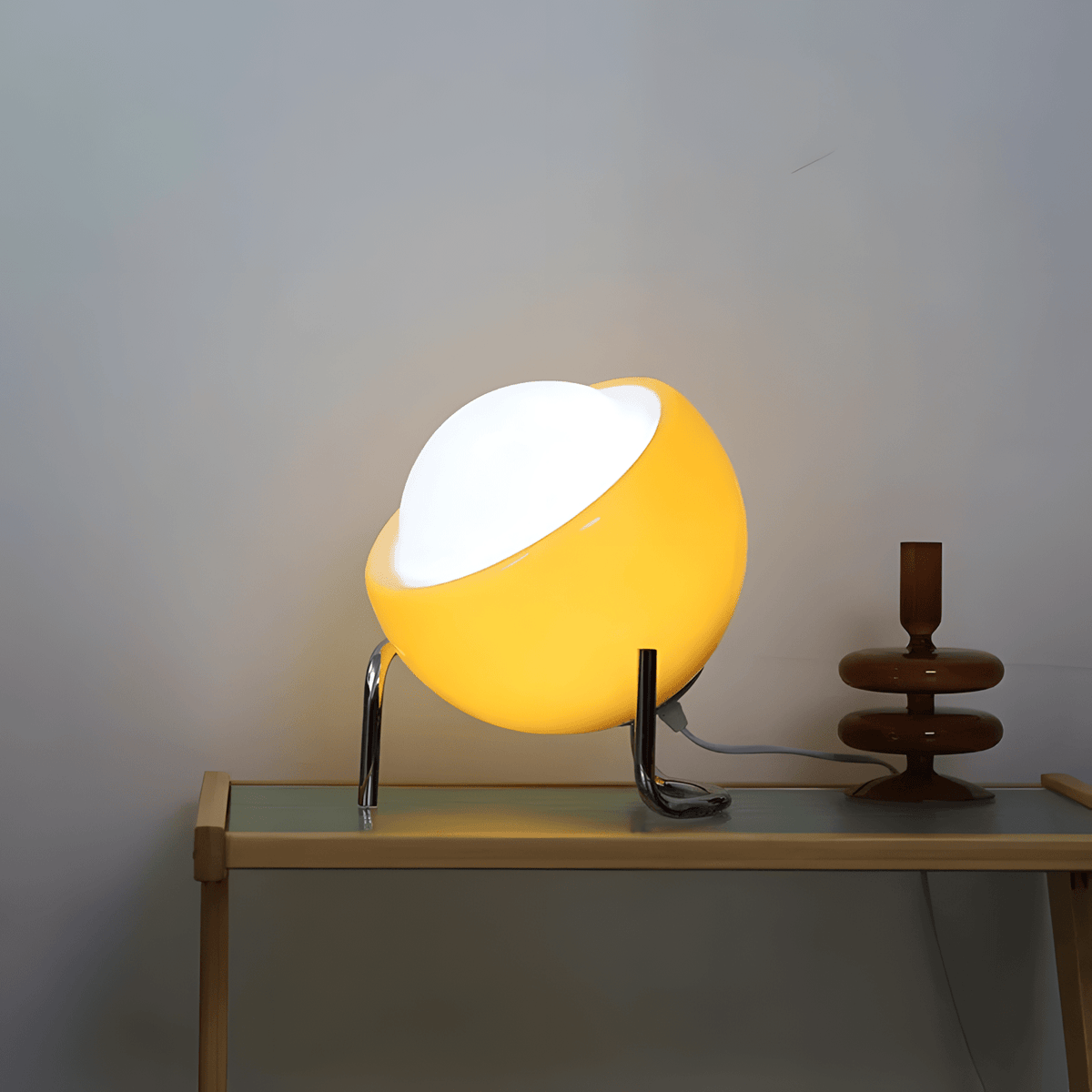 Bauhaus lampada da tavolo in vetro arancione e metallo cromato: lampada accesa su una consolle con specchio rotondo, vista di tre quarti - Luximode