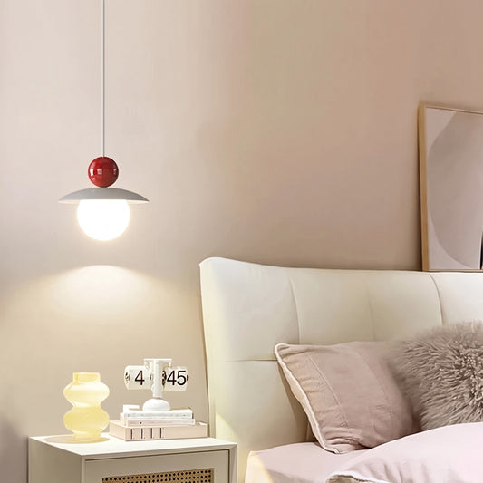 Lampada a sospensione Burano con sfera rossa accesa accanto al letto