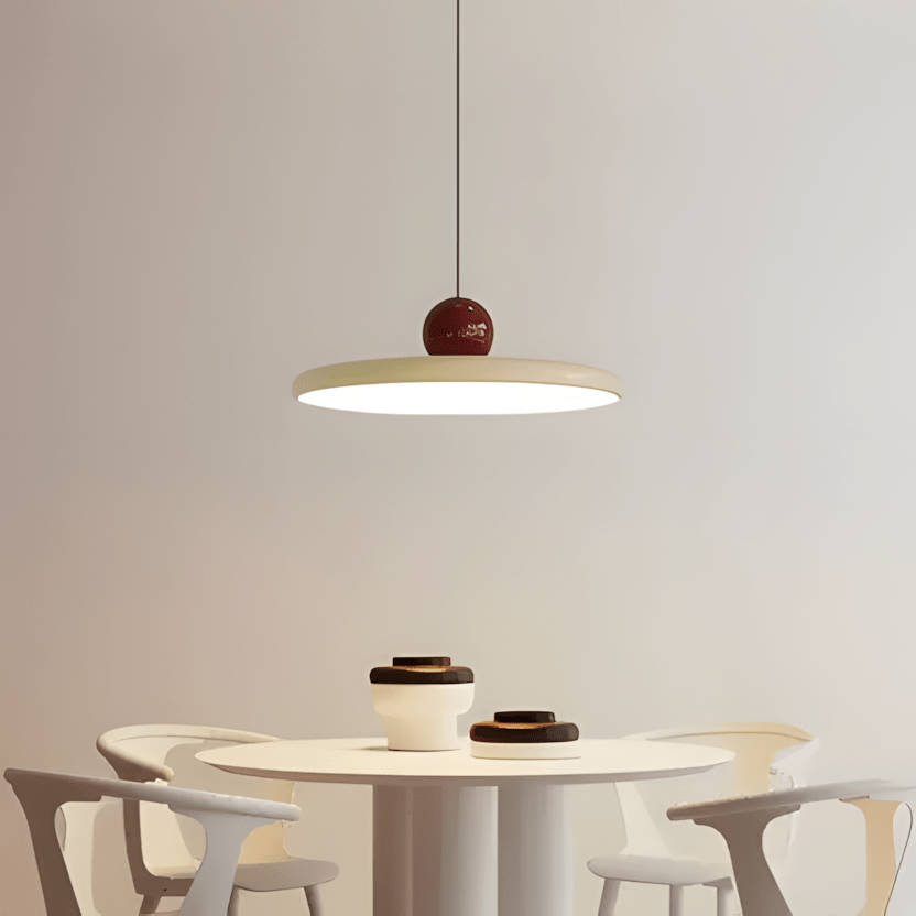 CeraVolta beige con sfera bordeaux sopra un tavolo rotondo bianco