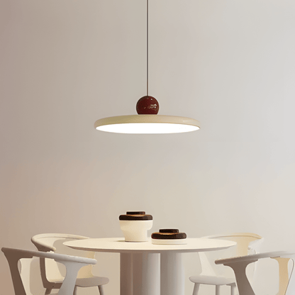 CeraVolta beige con sfera bordeaux sopra un tavolo rotondo bianco