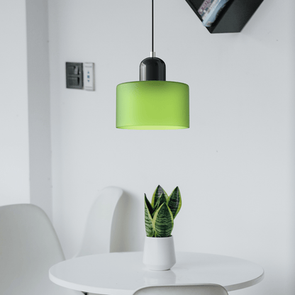 Croma in vetro verde opaco con base nera accesa sopra un tavolino bianco con pianta