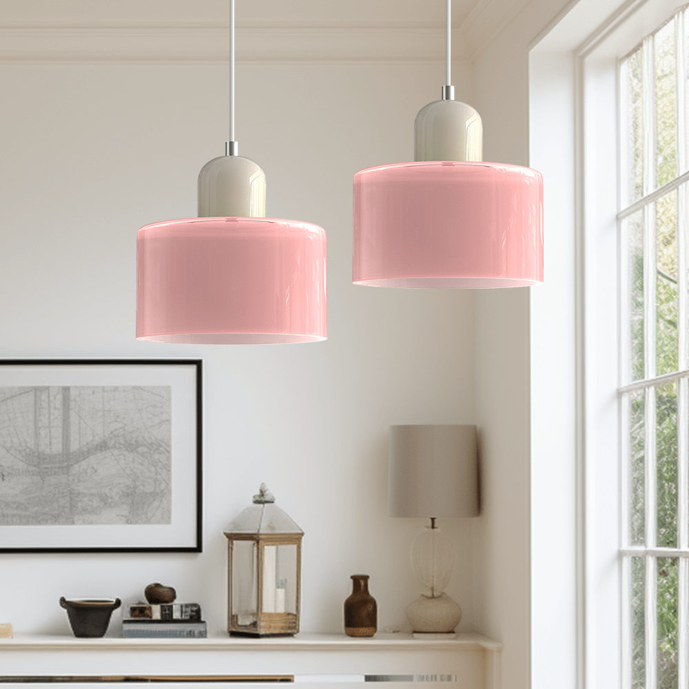 Due lampade Croma in vetro rosa chiaro con base beige accese accanto a una finestra