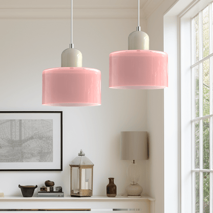 Due lampade Croma in vetro rosa chiaro con base beige accese accanto a una finestra