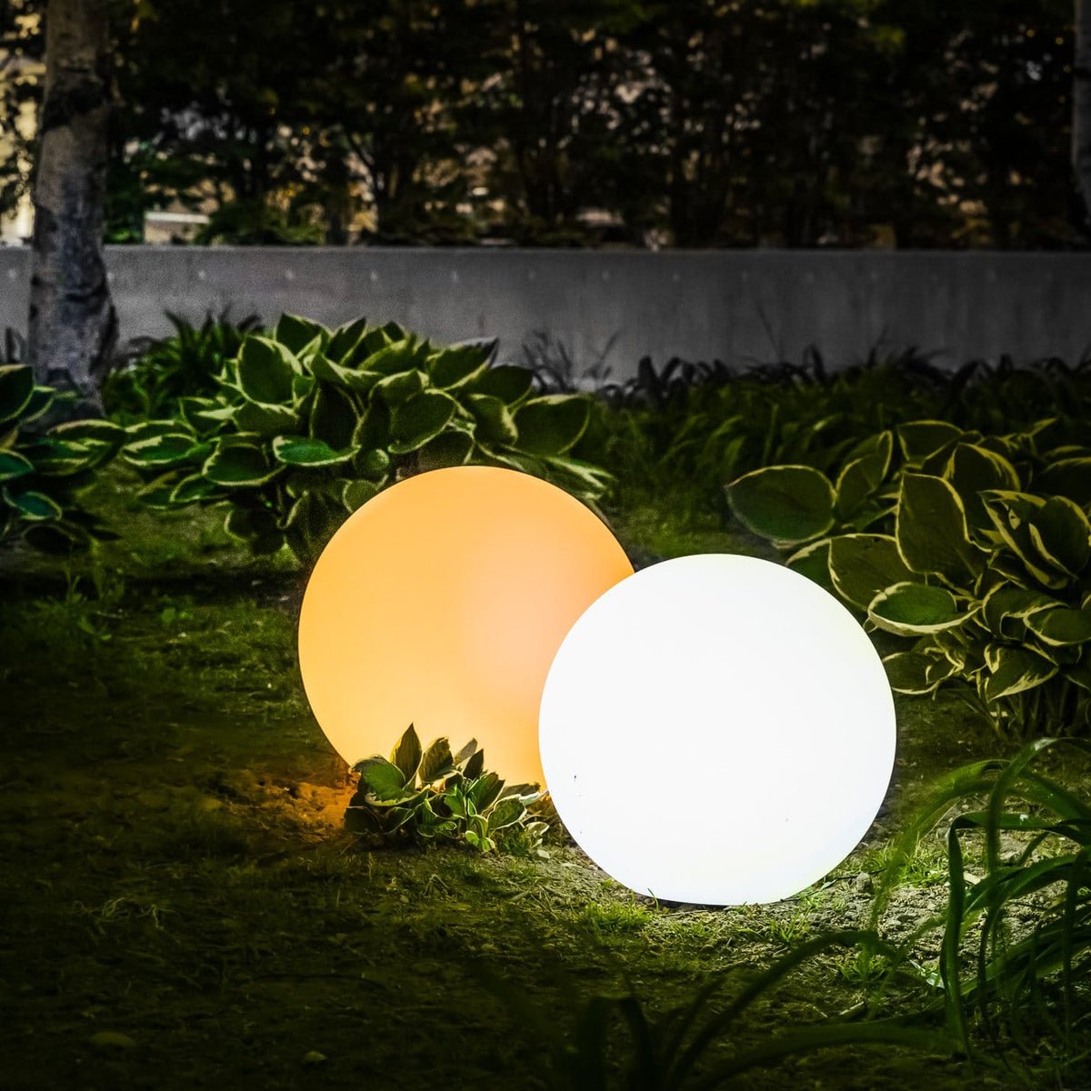 ElementLamp lampada portatile a sfera ricaricabile per interni ed esterni: due sfere accese in un giardino tra le piante di notte - Luximode
