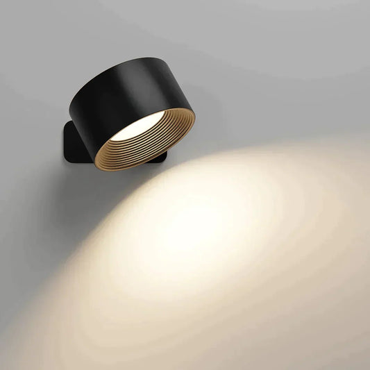 FlexiLamp lampada da parete ricaricabile con rotazione a 360 gradi: versione nera accesa su parete grigia con fascio di luce verso il basso - Luximode
