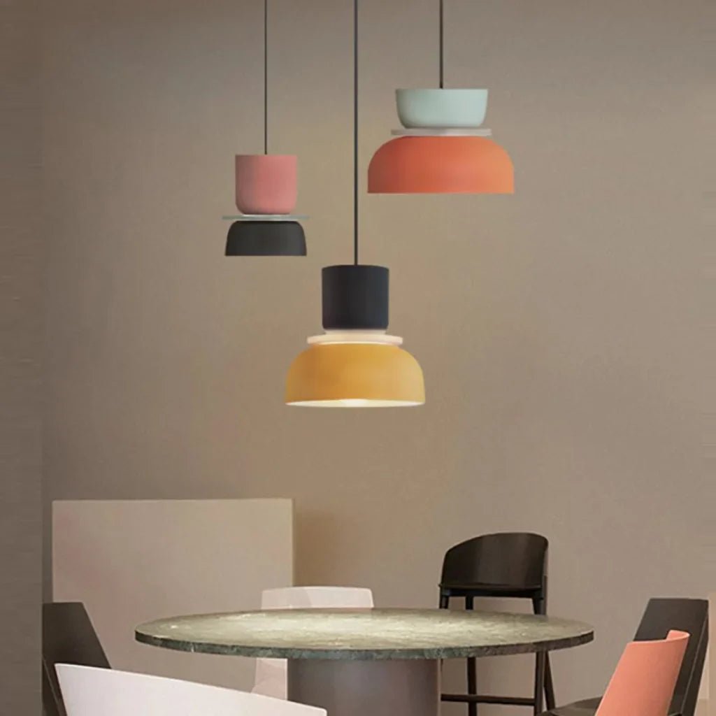 LucieBlock lampada a sospensione nordica in alluminio e acrilico: tre sospensioni rosa, gialla e nera in una sala da pranzo beige - Luximode