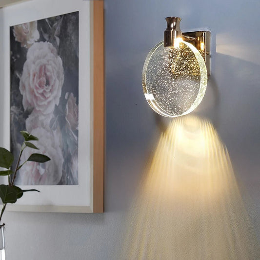 LuxeCircle applique da parete circolare LED in alluminio e acrilico: applique accesa con fascio di luce verso il basso accanto a un quadro floreale - Luximode