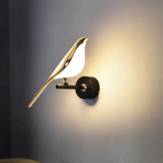 Applique MrBird a forma di uccello dorato accesa su parete scura