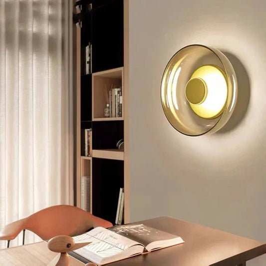 NordicScone lampada da parete elegante con diffusore in vetro: applique in vetro ambrato accesa sopra la scrivania di uno studio con libreria - Luximode