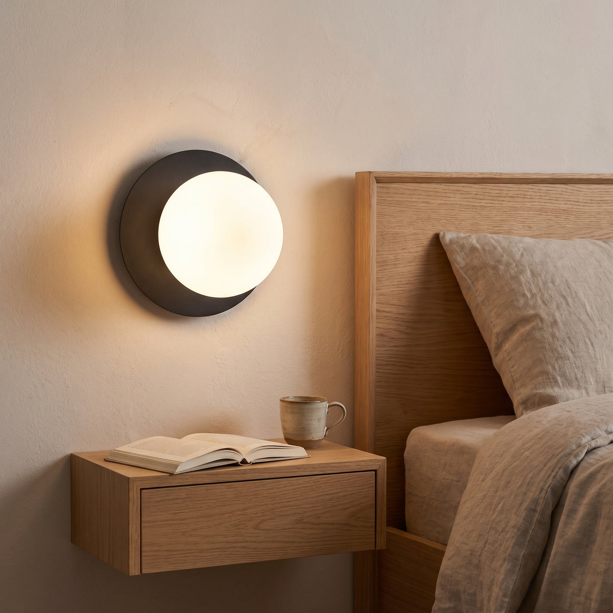 Applique Ostuni nera accesa accanto al letto, come luce da comodino
