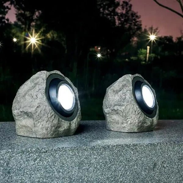 RockyLight lampada solare da esterno a forma di pietra: due lampade accese su un vialetto di ghiaia di notte - Luximode