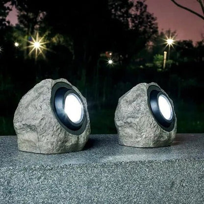 RockyLight lampada solare da esterno a forma di pietra: due lampade accese su un vialetto di ghiaia di notte - Luximode