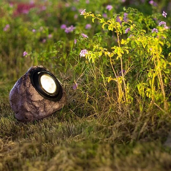RockyLight lampada solare da esterno a forma di pietra: lampada accesa tra le piante fiorite di un giardino al tramonto - Luximode
