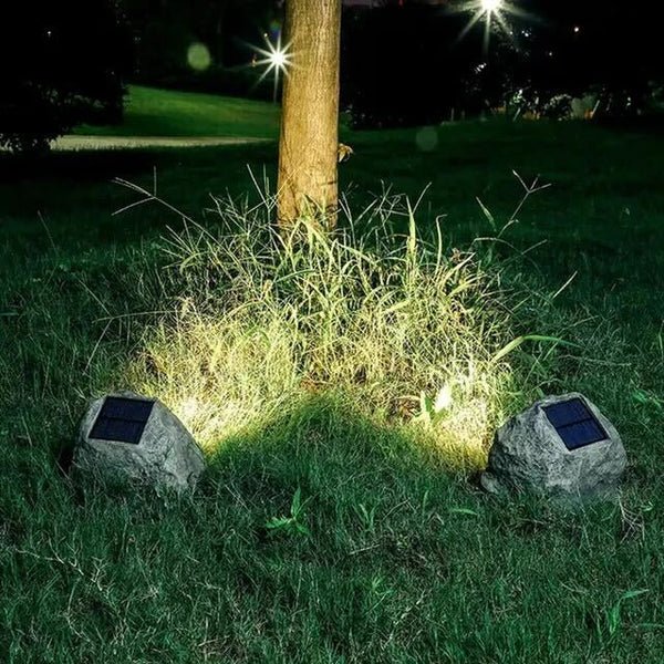 RockyLight lampada solare da esterno a forma di pietra: due lampade accese ai piedi di un albero nel prato - Luximode
