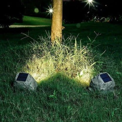 RockyLight lampada solare da esterno a forma di pietra: due lampade accese ai piedi di un albero nel prato - Luximode