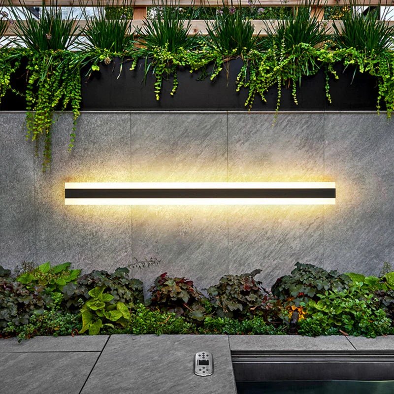 VistaBeam lampada da parete esterna impermeabile a barra LED: barra orizzontale accesa su un muro da giardino con piante rampicanti - Luximode